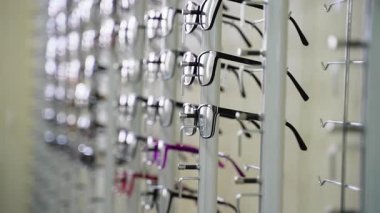 Metal ekran standı, bir optik mağazada müşteriler için farklı tarz ve renkleri gösteren çeşitli gözlük çerçeveleri sunar, göz giyimi seçeneklerinin görsel olarak çekici bir sunumunu yaratır