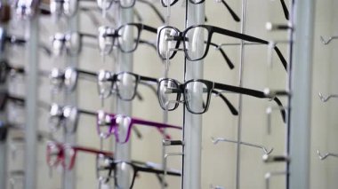 Modern optik mağazada ekran standında dönen birden fazla gözlük, çeşitli çerçeve stilleri, renkleri ve tasarımları vizyon düzeltme ve moda aksesuarları arayan algılayıcı müşteriler için gösteriyor