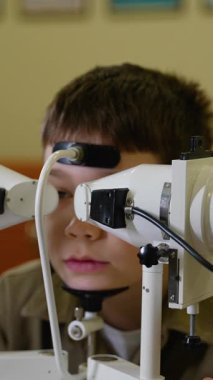 Tıp uzmanları, özel ekipman kullanan ve klinik ortamda görme ve göz sağlığını değerlendiren bir çocuk üzerinde göz muayenesi yapıyorlar.