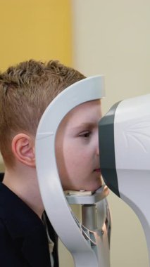 Tıp uzmanları genç bir çocuğun vizyon ve göz sağlığını değerlendirmek için ileri seviye teşhis ekipmanları kullanarak göz muayenesi yapıyorlar.