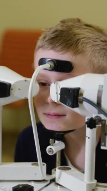 Tıp uzmanları, özel ekipman kullanan genç bir çocuk üzerinde detaylı bir göz muayenesi yaparak, olası görme sorunlarının kesin teşhisi ve tedavisini sağlıyorlar.