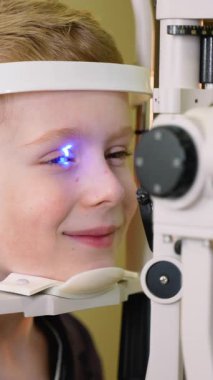 Pediatrik göz doktoru kapsamlı göz muayenesi yapıyor, özel kesik lamba teşhis ekipmanları kullanarak genç hastaların göz sağlığı üzerinde dikkatlice değerlendirme yapıyor.