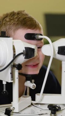 Tıp uzmanları, özel ekipman kullanan genç bir çocuk üzerinde eksiksiz bir göz muayenesi yaparak, olası görme sorunlarının kesin teşhisi ve tedavisini sağlıyorlar.