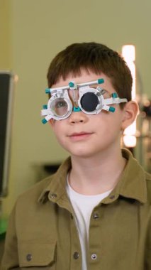 Profesyonel göz doktoru, genç hastaların vizyonlarını dikkatlice değerlendirirken, objektifin kesin tespiti ve pediatrik göz sağlığı değerlendirmesi için deneme çerçevesi kullanılıyor.