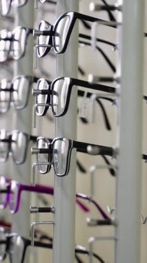 Bir optik mağazadaki dönen bir stantta, mükemmel çifti seçen müşteriler için çok çeşitli çerçeveler sunan çoklu gözlükler gösterilir.