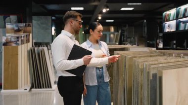 Profesyonel danışman bir müşteriye çeşitli fayans örnekleri gösteriyor, iyi stoklanmış bir hırdavatçıda yenileme projesi için en iyi seçimi yapmasına yardımcı oluyor.