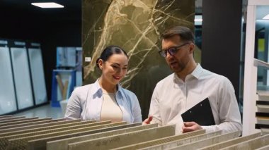 Profesyonel iç mimar müşteriye çeşitli fayans örnekleri sunar, dokuları, renkleri ve projeleri için uygunluğu tartışır