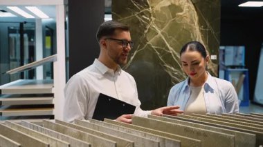 Modern sergi salonundaki tasarım seçeneklerini ve materyalleri dikkatlice açıklayarak, kiremit seçim sürecinde müşteriye rehberlik eden profesyonel iç mimari danışmanı