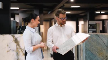 Profesyonel danışman modern bir galeride çeşitli fayans seçeneklerini bir kadına gösteriyor. Proje için dokuları, renkleri ve uygunluğu tartışıyor.