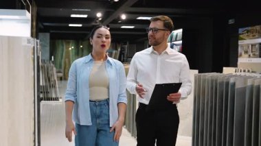 Büyük seramik fayanslara göz gezdirirken, gelecek yenileme projesi için çağdaş sergi ortamında renk, doku ve stili tartışırken, iç tasarım profesyoneli satıcıya bağlanıyor.