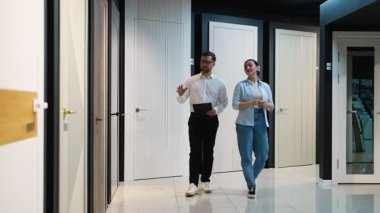 Profesyonel danışman, bir kadına galeride farklı kapılar gösteriyor, özellikleri, stilleri tartışıyor ve ev yenileme projesi için en iyi seçimi yapmasına yardım ediyor.