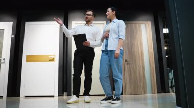 Profesyonel danışman galeride bir kadına çeşitli kapı modellerini gösteriyor, özellikleri tartışıyor ve ev yenileme projesi için doğru seçimi yapmasına yardım ediyor.