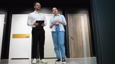 Profesyonel danışman, galeride kadın bir müşteriye çeşitli kapı modellerini gösteriyor, özellikleri tartışıyor ve ev yenileme projesi için doğru seçimi yapmasına yardım ediyor.