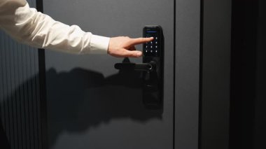 Profesyonel işadamı dijital elektronik kapı kilidine güvenli bir şekilde giriş kodu girerek, ev veya ofis girişi için modern güvenlik teknolojisini gösteriyor