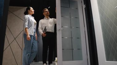 Mobilya mağazasındaki bir çifte farklı kapı seçenekleri sunan profesyonel iç mimar ev yenileme projeleri için mükemmel olanı seçmelerine yardım ediyor.