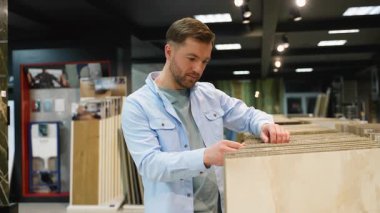 Profesyonel mimar modern sergi salonundaki malzeme seçeneklerini karşılaştırırken seramik fayans örneklerini dikkatlice seçiyor, inşaat projesi için tasarım olanaklarını değerlendiriyor