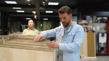 Seramik seramik seçilim süreci donanım mağazasında devam ediyor, müşteriler malzemelerin karşılaştırılması sırasında profesyonel danışmanlık yapıyorlar, ev yenileme projesi için renkler