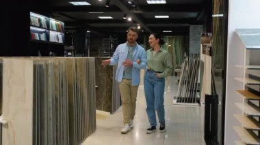 Yeni daireleri için fayanslar seçen genç bir aile, profesyonel iç mimarın rehberliğinde bir galeride seçenekleri ve malzemeleri tartışıyor.