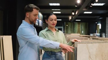 Modern bir galeride müşteriye çeşitli fayans seçeneklerini sunan profesyonel danışman kadın, malzeme, tasarım ve yenileme projesi için uygunluğu tartışıyor.