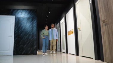 Sergi salonunda iç mimar danışmanıyla işbirliği yapan genç aile, sürmekte olan ev yenileme projesi için şık kapılar seçiyor, kalite ve tasarım seçeneklerini birlikte değerlendiriyor.