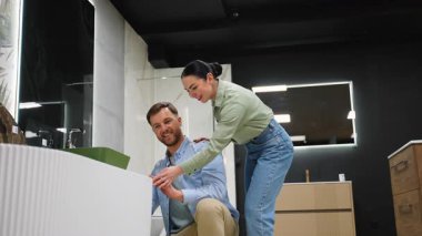 Profesyonel danışman, bir mobilya mağazasında modern bir banyo lavabosu seçerken bir çifte yardım ediyor ve yenileme projesinde rehberlik ve danışmanlık yapıyor.