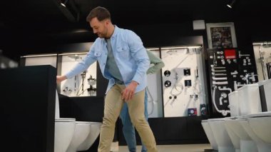 Banyo eşyaları mağazasında çok çeşitli ürünler sunuluyor. Danışman bir kadın yeni bir tuvalet seçerken bir çifte yardım ediyor. Farklı seçenekleri incelerken tavsiye ve rehberlik sunuyorlar