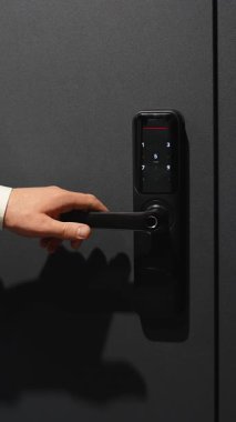 Beyaz gömlekli işadamının elini siyah kapıya elektronik dijital şifreyle kilitle, doğru kombinasyonu seç ve kapıyı aç.