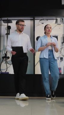 Profesyonel tasarım danışmanı müşteriye banyo armatür seçimi yoluyla rehberlik eder, çeşitli seçenekler sunar ve modern sergi salonu ortamında uzman tavsiyesi sunar