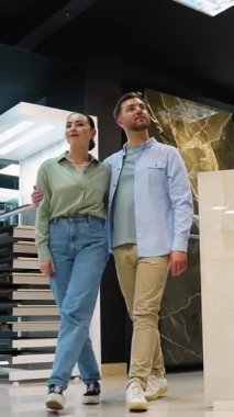 Evli çiftin modern sergi salonunda fayans seçimi, ev yenileme projesi için iç tasarım seçeneklerini değerlendirirken profesyonel tasarım danışmanıyla yakın çalışma