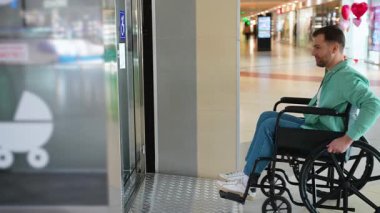 Tekerlekli sandalye kullanıcısı modern alışveriş merkezi asansöründe geziniyor, şehir perakende ortamında bağımsızlığı ve ulaşılabilirliği gösteriyor