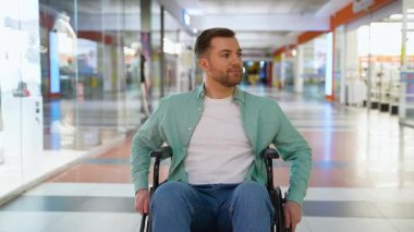 Kendine güvenen tekerlekli sandalye kullanıcısı geniş modern alışveriş merkezlerinde geziniyor, kişisel özgürlüğün tadını çıkarıyor ve kendine güvenerek bağımsız hareketlilik gösteriyor