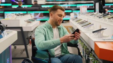 Elektronik mağazasında çalışan, mobil teknolojinin tadını çıkarırken akıllı telefon seçen, kişisel yetkilendirme ve tüketici yaşam tarzını sergileyen bağımsız bir adam.