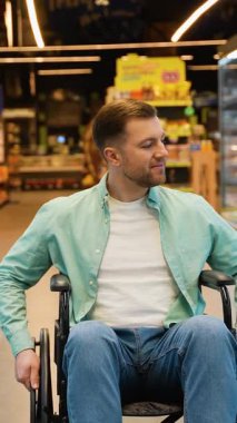 Taşınabilirlik engelli genç erkek dondurucu bölümde geziniyor, alışveriş seçerken perakende ortamında kişisel özerklik gösteriyor