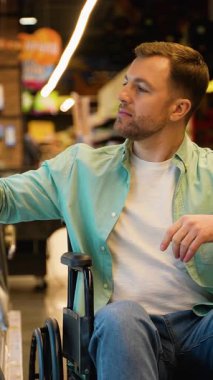 Engelli bir adam marketin koridorunda rahatça geziniyor, peyniri bağımsızlık ve neşe ile seçiyor ve perakende sektöründe kişisel özerkliğini sergiliyor.