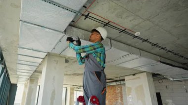 Profesyonel HVK uzmanı, inşaat halindeki bir binada havalandırma sistemi üzerinde çalışıyor. İşinde uzmanlık ve hassasiyet gösteriyor.