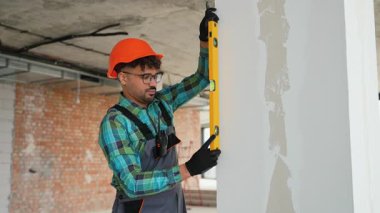 Profesyonel inşaatçı bina inşaatı sırasında bir duvarın dikey hizalanmasını sağlar, hassasiyeti ve standartlara uyumu gösterir