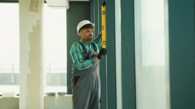 Profesyonel inşaatçı, bina inşaatı sırasında tam hizalama ve yapısal bütünlük sağlayarak, ruh düzeyini kullanarak pencere çerçevesinin dikeyliğini kontrol eder