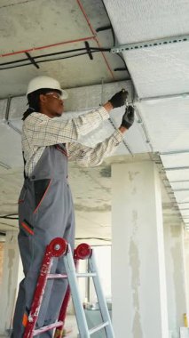 Elektrik tesisatı üzerine çalışan profesyonel elektrikçi, inşaat halindeki bir binaya dikkatlice kablolar yerleştiriyor, güvenlik ve hassasiyet sağlıyor.