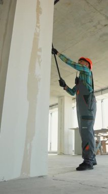 Profesyonel ressam, yeni konut inşaatı projesinde yüzeyi yenilemek için rulo kullanarak iç duvara beyaz astar takıyor.