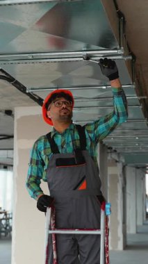 Profesyonel elektrikçi kısmen inşa edilmiş binanın içindeki merdivene havalandırma sistemi ekipmanları yerleştiriyor.