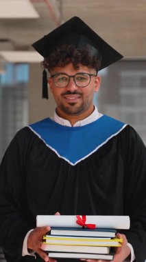 Mezuniyet elbisesi ve şapkası içinde özgüvenle gülümseyen, diploma ve ders kitaplarını tutan, akademik başarıyı ve kişisel başarıyı profesyonel portre serisi ile yakalayan mezun.