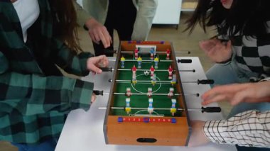 Enerjik genç öğrenciler, temiz beyaz arka planda oynarken, rekabetçi masa oyunu oynuyorlar, kahkahalarını ve arkadaşlıklarını paylaşıyorlar.