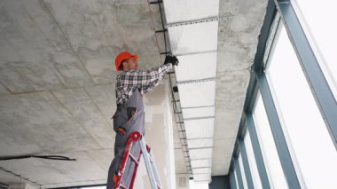 Tulumlu ve eldivenli teknisyen havalandırma kanalı kurulumunda çalışıyor.