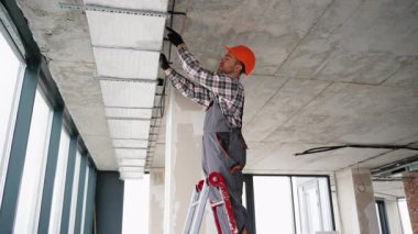 Modern bir ofis içinin tavanına havalandırma kanalları kuran ya da tamir eden işçi..