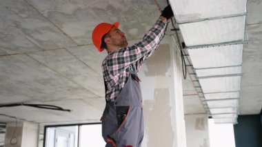 Üniformalı deneyimli işçiler, uygun hava akımı ve teknik havalandırma kurulumuna odaklanarak modern ofiste havalandırma sistemi kuruyor..