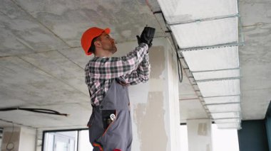 İş kıyafetlerinde uzman teknisyen ofis alanına tavan havalandırma ünitesi kurarak, uygun hava dolaşımını ve sistem verimliliğini sağlıyor.