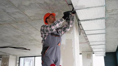 Üniformalı profesyonel işçiler, hava kalitesi ve hava akışı sistemini geliştirmek için çağdaş bir ofis içinde havalandırma kanalı işi yapıyor..