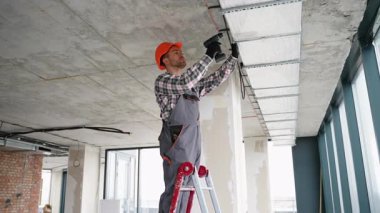 Üniformalı profesyonel işçiler, hava kalitesi ve hava akışı sistemini geliştirmek için çağdaş bir ofis içinde havalandırma kanalı işi yapıyor..