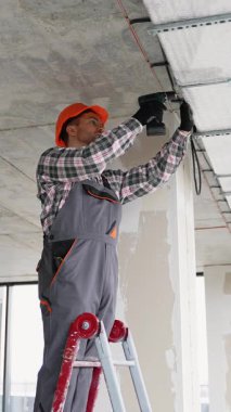 Tulumlu ve eldivenli teknisyen havalandırma kanalı kurulumunda çalışıyor..