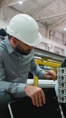 Kalite kontrol mühendisi titizlikle büyük bir sanayi fabrikasındaki alüminyum profilleri inceleyerek standartlara ve özelliklere uyulmasını sağlıyor.